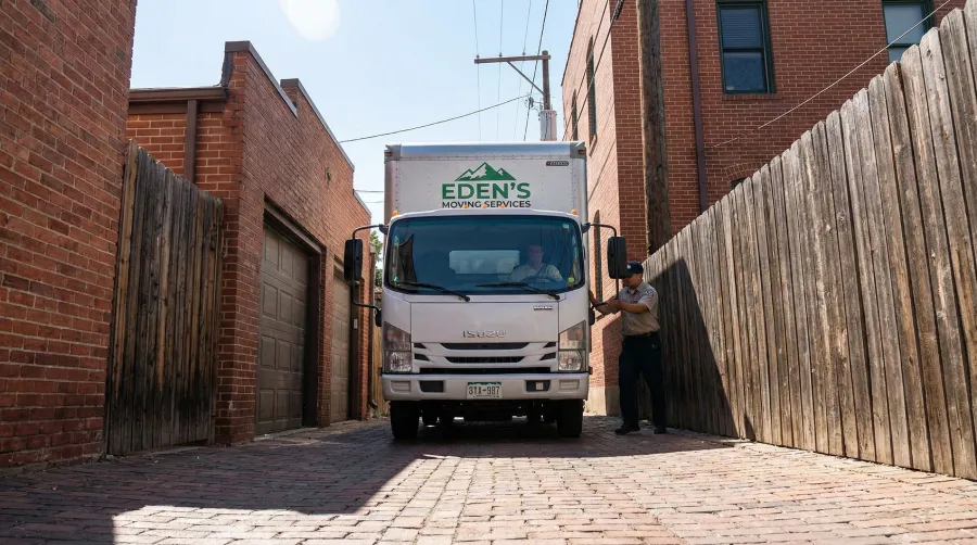 Eden's Moving Services truck expertly navigating a narrow brick alleyway in a dense Denver neighborhood like Capitol Hill, ensuring a low-stress transition that avoids blocking street traffic or disturbing neighbors.